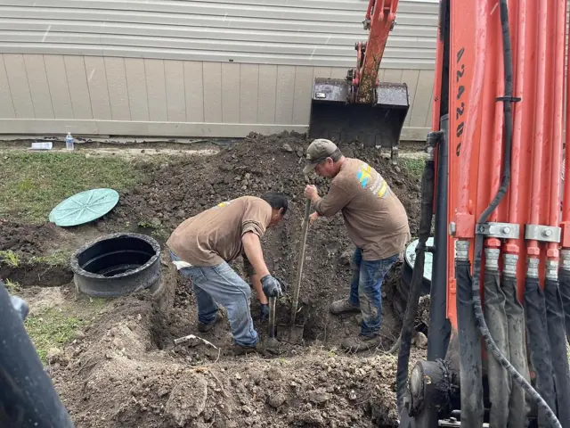 Crew uncovering a buried septic tank with an excavator