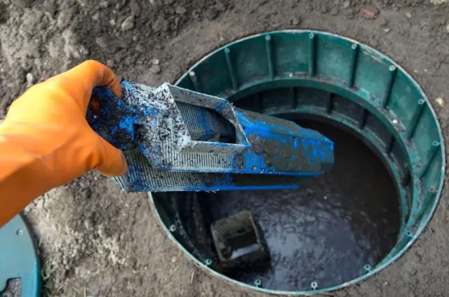 Gloved hand pulling an effluent filter out of a septic tank