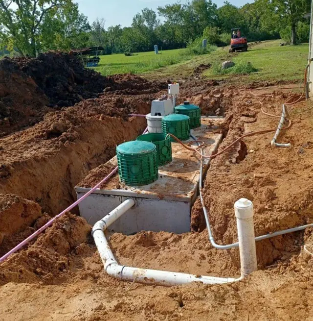 Septic tank install with PVC plumbing and green risers