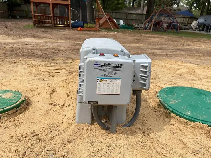 Aerobic septic control panel beside a tank lid