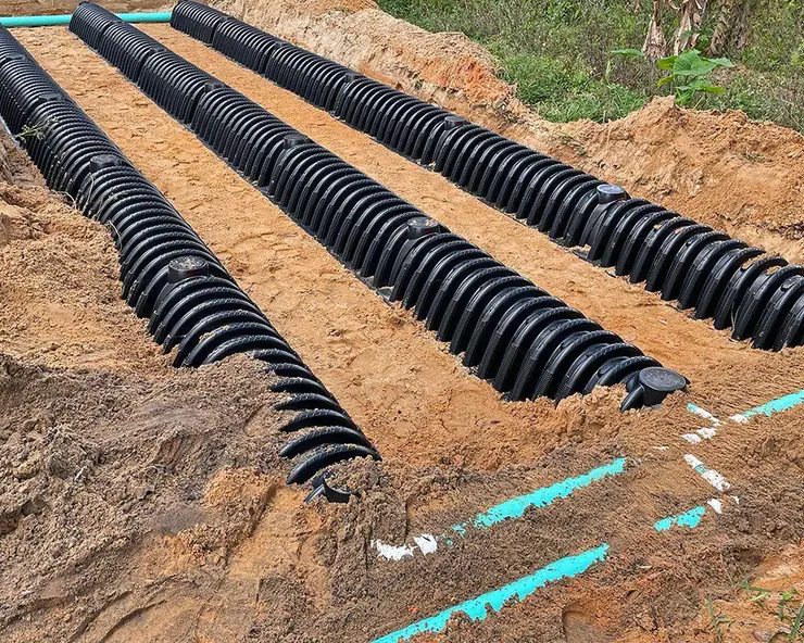 Corrugated drain field chambers being installed in an excavated field (drain field glossary guide)