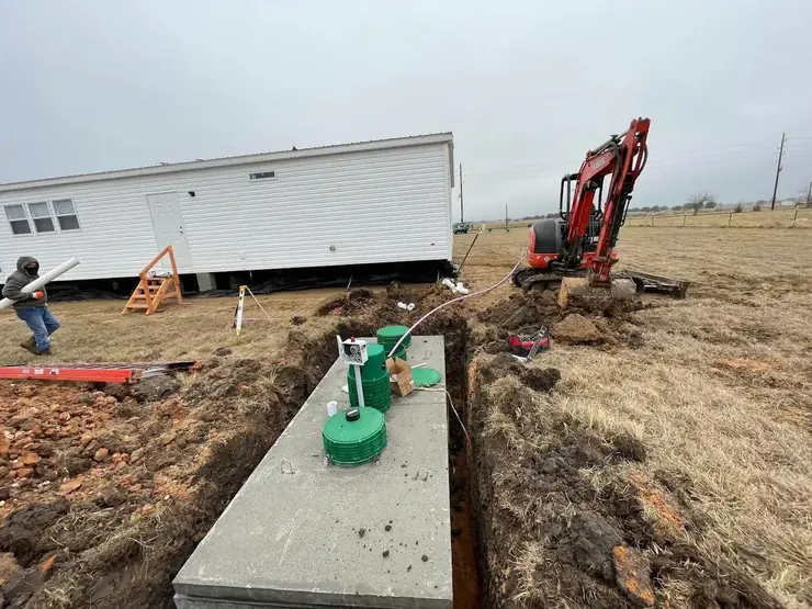 Septic tank set in a trench with an excavator working nearby