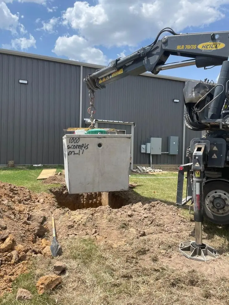 Concrete septic tank lifted into place by a crane truck