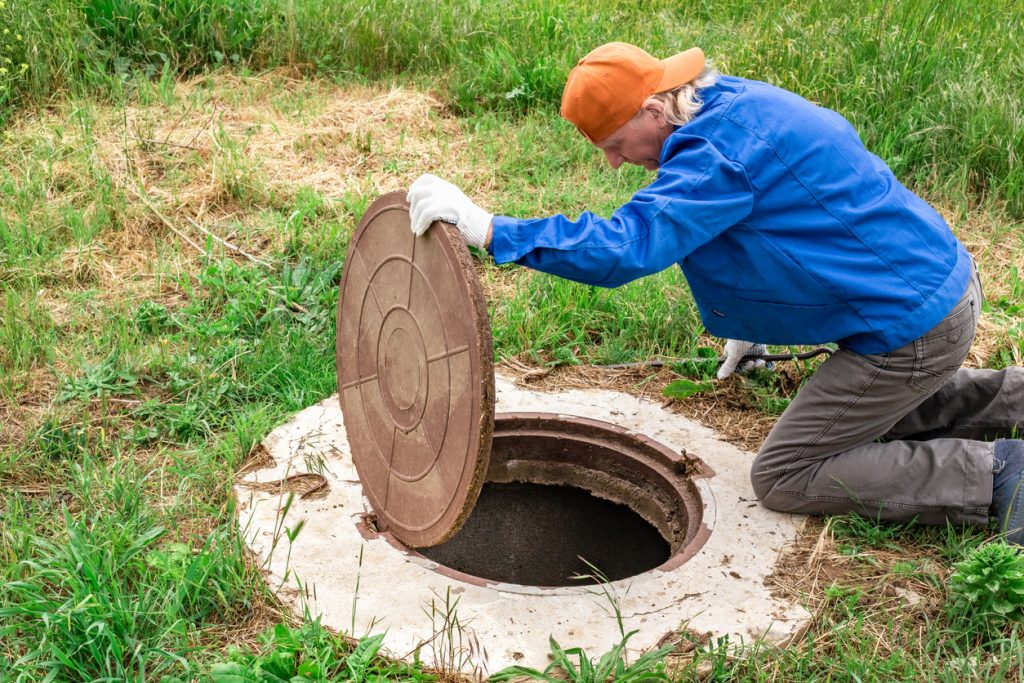 the man opened the cover of the sewer manhole to pump out the sewage.