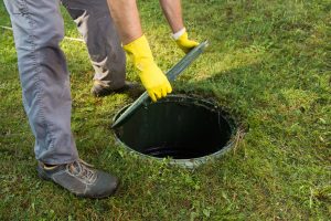 Opening septic tank lid. Cleaning and unblocking septic system and draining pipes.